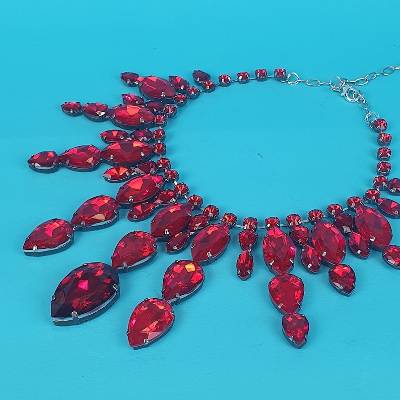 May include: A red crystal necklace with a silver chain and multiple teardrop-shaped crystals.
