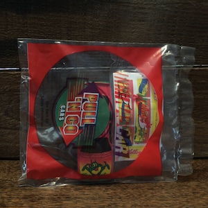 May include: A red, white, and green toy car package with the words "Pull 'n Go Cars" on the front. The package is sealed in clear plastic.