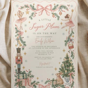 Könnte beinhalten: Eine rechteckige Einladungskarte mit gewelltem Rand und einer Aquarellillustration eines Nussknackers, Ballerinas, eines Hasen, eines Weihnachtsbaums und Geschenken. Der Text lautet A LITTLE Sugar Plum IS ON THE WAY, zu Ehren von Emily Wilson, 4. Dezember um 13 Uhr, The Tea Room, 123 Sugarplum Way, Franklin, TN, RSVP 123-456-7890, Registered at Target & Amazon.