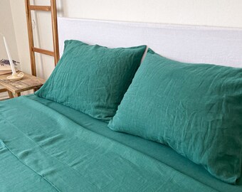 May include: A teal green linen bedding set with two pillowcases and a flat sheet. The bedding is made from a soft, breathable fabric and is perfect for a cosy night's sleep.