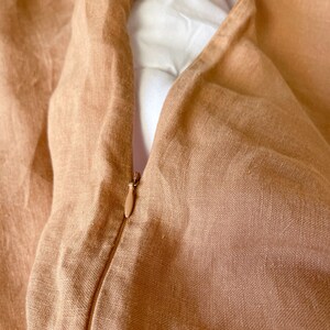 May include: A close-up of a tan linen duvet cover with a zipper closure. The zipper is visible and the fabric is textured.