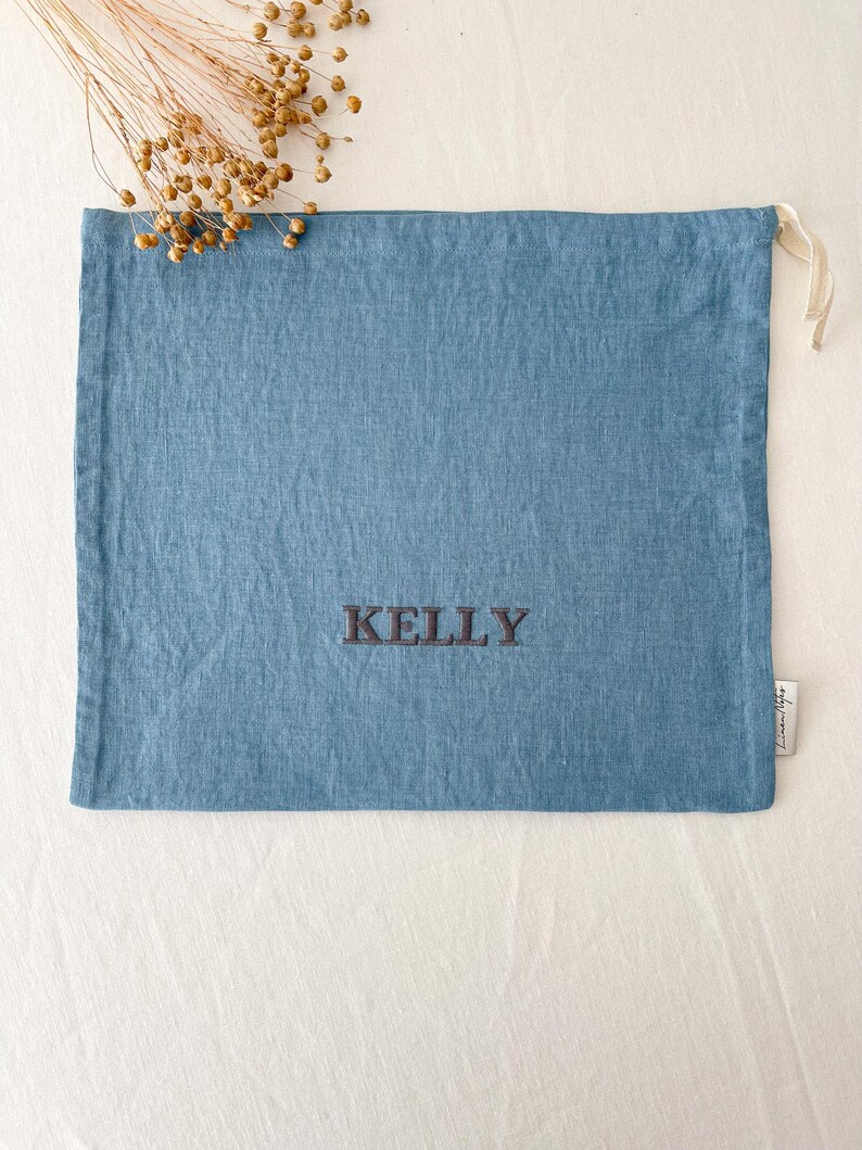 May include: A blue linen drawstring bag with the name "KELLY" embroidered in black thread.