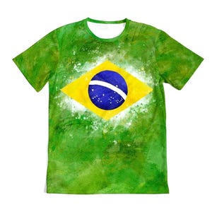 May include: Green t-shirt featuring the Brazilian flag. The shirt has a watercolor effect with a green background and a yellow diamond containing a blue circle with white stars and a white band.