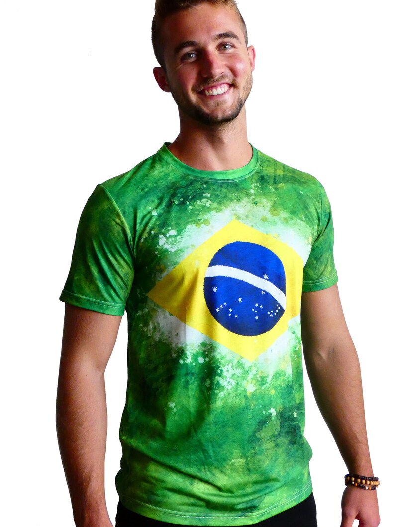 May include: Green t-shirt featuring the Brazilian flag. The shirt has a vibrant green background with white accents and the flag's yellow diamond, blue circle, and star pattern prominently displayed on the front.