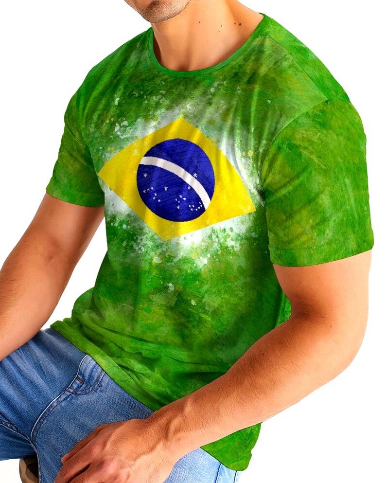 May include: Green t-shirt featuring the Brazilian flag. The shirt has a yellow diamond with a blue circle and white stars in the center. The shirt is a vibrant green with a watercolor effect.