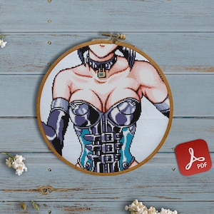 May include: A cross-stitch embroidery hoop with a colorful image of a woman wearing a blue and silver corset. The hoop is on a light blue wooden surface.