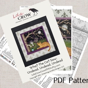 May include: A cross stitch pattern titled "What the Cat Saw: Undead, Undead, Undead" by Lola Crow Cross Stitch. The pattern features a cat looking out a window at a spooky scene with a full moon, a tree, and a tombstone.