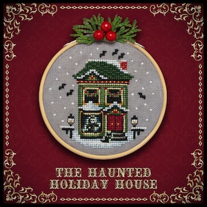 May include: A cross-stitch embroidery hoop with a gray background and a green house with a red door. The house has a snowy roof and is decorated with lights. The text "THE HAUNTED HOLIDAY HOUSE" is below the hoop.