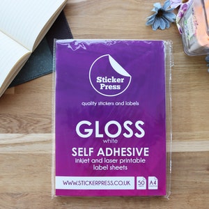 May include: A package of 50 white gloss self-adhesive A4 label sheets. The package is purple and has the text "Sticker Press" and "quality stickers and labels". The package also has the text "GLOSS white SELF ADHESIVE inkjet and laser printable label sheets" and "WWW.STICKERPRESS.CO.UK".