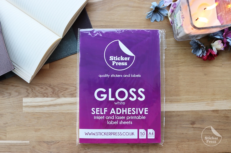 May include: A package of 50 white gloss self-adhesive A4 label sheets. The package is purple and has the text "Sticker Press" and "quality stickers and labels". The package also has the text "GLOSS white SELF ADHESIVE inkjet and laser printable label sheets" and "WWW.STICKERPRESS.CO.UK".