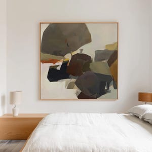 Könnte beinhalten: Abstrakte Kunstmalerei mit Holzrahmen. Das Kunstwerk zeigt eine Komposition aus sich überlappenden Formen in Grau-, Braun- und Beigetönen mit Akzenten in Orange und Gelb. Das Gemälde hängt über einem Bett mit weißer Bettwäsche.