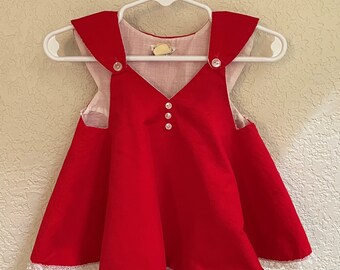 I bambini piccoli di Bryan degli anni '70 indossano un vestito in velluto a coste rosso con copri pannolino coordinato