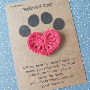 May include: A brown card with the text "Beloved Dog" and a black paw print. A pink crocheted heart is attached to the card with the text "A little heart of love I send as I know you miss your faithful friend, remember you're never far apart your little friend lives in your heart x".