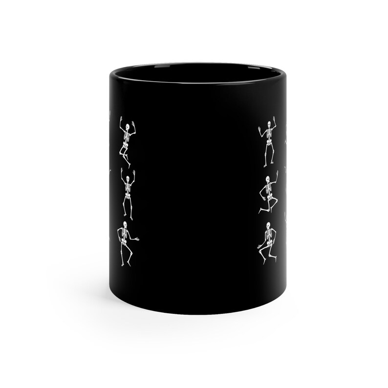 May include: Black ceramic coffee mug with a white outline of skeletons dancing on the sides.