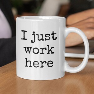 May include: White ceramic coffee mug with black text that reads "I just work here".