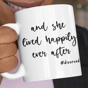 May include: White ceramic coffee mug with black text that reads "and she lived happily ever after #divorced".