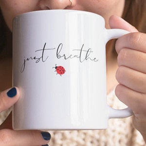 May include: White ceramic mug with a black and white design that says "just breathe" with a small red ladybug illustration.