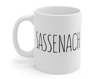 May include: White ceramic mug with a black inscription that reads "SASSENACH".