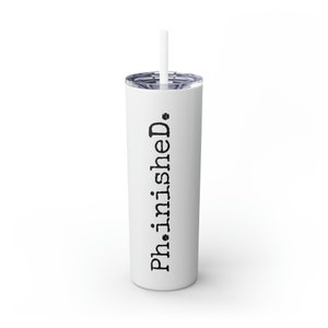May include: White stainless steel tumbler with a black inscription that reads "Phinished". The tumbler has a straw.