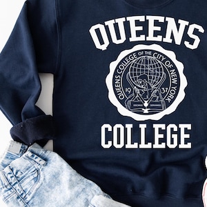 May include: Navy blue sweatshirt with white text that reads "Queens College" and a white logo featuring a globe and the words "Queens College of the City of New York 1937".