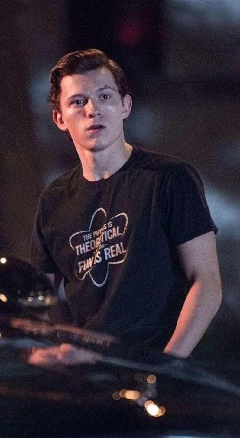 May include: A young man wearing a black t-shirt with a white graphic that says "The physics is theoretical, fun is real".