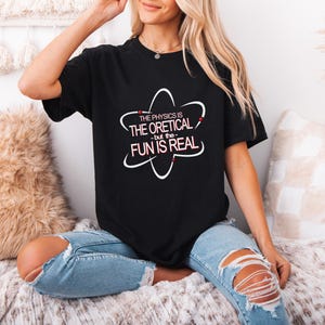 May include: A black t-shirt with a white atom graphic and the text "The physics is the oretical - but the fun is real".