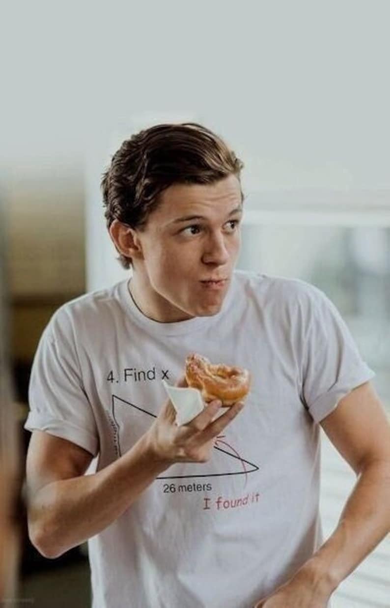 May include: A person wearing a white t-shirt with a math problem printed on it. The problem is a right triangle with the text "4. Find x" and "26 meters" written on it. The person is holding a donut in their right hand.