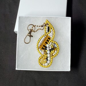 May include: A gold and white beaded treble clef keychain with a silver chain and clasp.