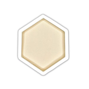 May include: A white hexagonal sticker with a beige center. The sticker has a slightly raised edge.