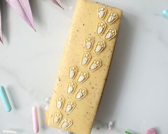May include: A yellow rectangular cake bar decorated with white paw prints in a diagonal line.