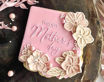 May include: Pink and white decorated sugar cookie with the text "Happy Mother's Day" in white icing.