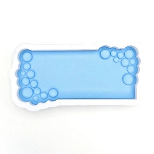 Könnte beinhalten: Ein weißer Plastik-Ausstecher in Form eines Rechtecks mit einem blauen Blasenrand auf einer Seite.
