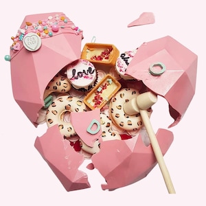 May include: A pink heart-shaped chocolate box is broken open with a wooden mallet. The box is filled with donuts, cupcakes, and other treats. The box has the words "For Ever" and "Love" on it.