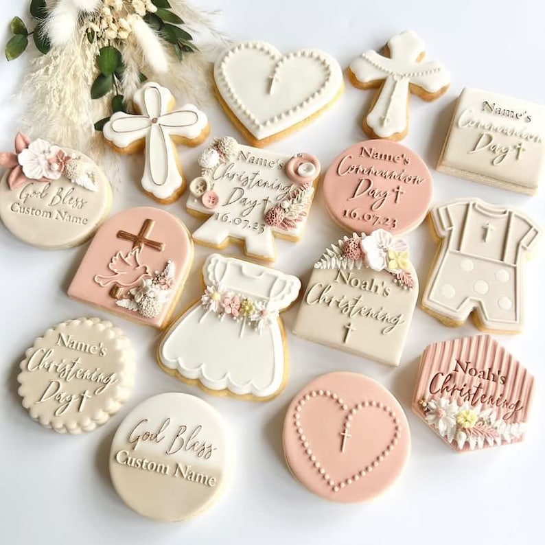 Puede incluir: Surtido de galletas de az&uacute;car decoradas para un bautizo. Las galletas presentan varios dise&ntilde;os, incluyendo una cruz, un coraz&oacute;n, un vestido, un mono de beb&eacute; y un cartel con el texto "D&iacute;a del Bautismo de [Nombre]".
