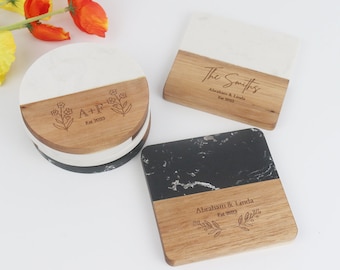 May include: Set of four coasters with a marble and wood design. The coasters feature personalized engravings with names and dates. The coasters are round and square.
