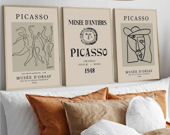 May include: Three framed art prints featuring Picasso's artwork. The prints have a beige background with black text and line drawings. The middle print says "Musée D'Antibes" and "1948". The other two prints say "Picasso" and "Musée D'Orsay".