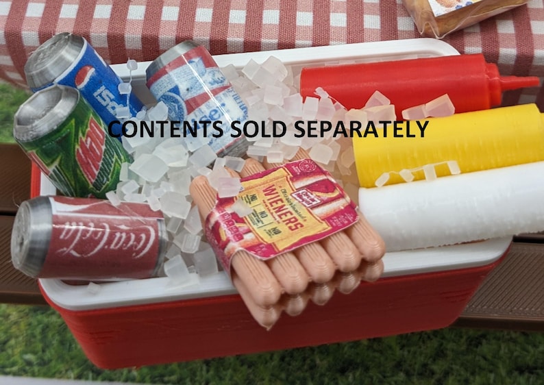 May include: A miniature red and white cooler filled with ice cubes, soda cans, and a package of wieners. The cooler also contains red ketchup and yellow mustard bottles. The text "CONTENTS SOLD SEPARATELY" is visible.