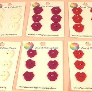 May include: Six white, six purple, and six red lip-shaped buttons on cards with the text "Love of Color Studio" and a website address.