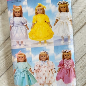 May include: A vintage Butterick sewing pattern showing six doll dress designs. The pattern cover features illustrations of dolls in different dresses, including a yellow dress, a blue dress, and a pink dress. The pattern number is 5329.