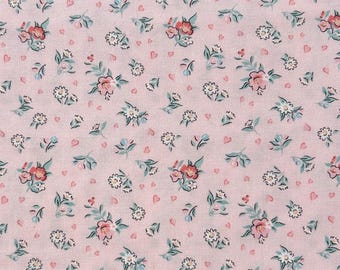 Può includere: Primo piano di un tessuto rosa con un motivo floreale ripetuto. Il design presenta piccoli gruppi di fiori rosa e rossi, margherite bianche e foglie azzurre, intervallati da piccoli cuori rosa.