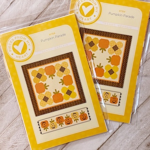 Peut inclure: Deux patrons de couture en papier jaune et brun pour le quilting. Les patrons sont intitulés "Pumpkin Parade" et présentent un logo en forme de cœur avec le texte "Pieces From My Heart".