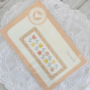 Peut inclure: Un modèle de courtepointe rose et blanche avec le titre "Tulip Festival #027" et le texte "Pieces From My Heart" par Sandy Gervais.