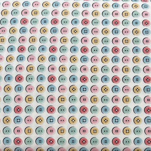 May include: A fabric pattern featuring a repeating design of colorful buttons. The buttons are in shades of pink, blue, yellow, and green, each with a black center and a cross-shaped stitch detail. The background is a light cream color.