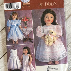 May include: Simplicity 18" Dolls sewing pattern featuring doll dresses. The cover includes images of dolls in various dresses, including a blue dress with lace trim and a pink dress with a teddy bear. The pattern is labeled "Fancy Frocks".