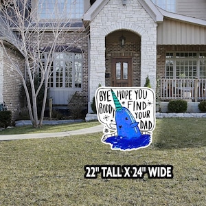 May include: A whimsical yard sign featuring a blue narwhal with a unicorn horn and the text "Bye Buddy, Hope You Find Your Dad." The sign is 22 inches tall and 24 inches wide, placed in front of a house with a stone facade.