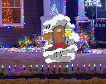 May include: A whimsical outdoor Christmas decoration shaped like a snow-covered rock formation with a wooden door. The sign reads "The Mean One" and "Unwelcome". A sign on the door says "Go Away!" and the number "2". The decoration is surrounded by colorful Christmas lights.