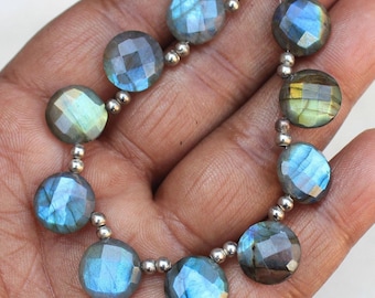 May include: A strand of round, faceted labradorite beads with iridescent blue and green hues. The beads are strung on a silver wire with silver spacer beads.