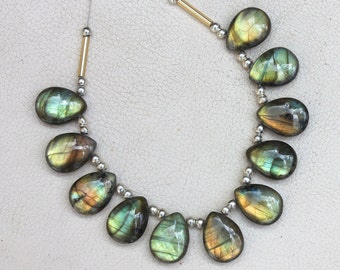 Könnte beinhalten: Eine Kette aus tropfenförmigen Labradorit-Edelsteinen, die auf einer silbernen Kette mit goldenen Zwischenstücken aufgefädelt sind. Die Perlen sind eine Mischung aus Grün und Gold mit irisierenden Schimmern.
