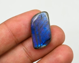 May include: A blue and grey labradorite gemstone with iridescent flashes of colour. The gemstone is irregularly shaped and has a smooth, polished surface.