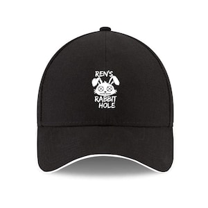 May include: Black baseball cap with a white brim. The cap features the text "REN'S RABBIT HOLE" in white, along with a graphic of a rabbit's face. The cap is a classic style with a curved brim.